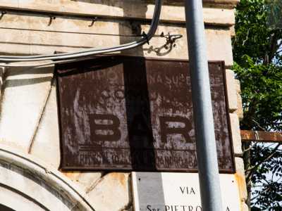 La facciata in pietra chiara con eleganti rifiniture e ampio portale marmoreo,  mostra un�oramai quasi illeggibile insegna in ferro erosa dalla ruggine che tenta di occultare la dicitura �Campo benzina Superiore, Comune di Bari�